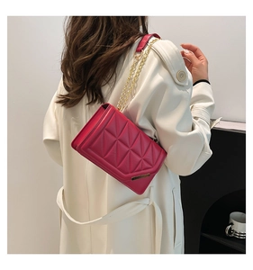Detailed close-up of fuchsia quilted leather crossbody bag with gold chain strap on model