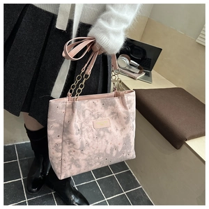Pink tote bag detail with star moon prints and metal chain straps on office desk
