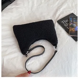 Detail einer schwarzen Plüschtasche mit Teddy-Wolltextur und verstellbarem Ledergurt
