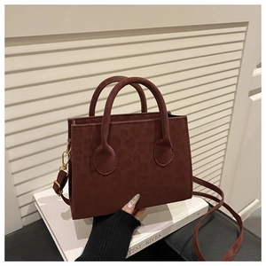 Détail du sac bandoulière marron rouge à motif léopard avec bandoulière amovible sur livre