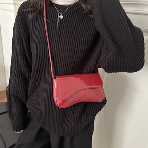 Glänzende tiefrote Lackleder-Umhängetasche kombiniert mit einem schwarzen Rollkragenpullover