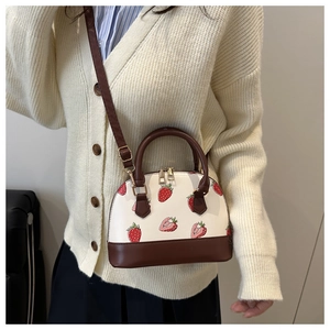 Détail du sac coquillage à fraises blanc avec poignées en cuir marron et métal doré