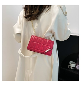 Detailed view of red quilted bag with gold chain strap on beige trench coat outfit