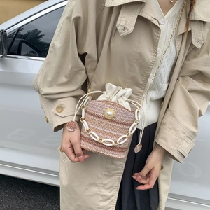 Woven straw bucket bag with white drawstring closure and pearl chain strap detail