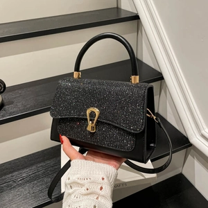 Elegante borsa a mano con paillettes nere, fibbia dorata e tracolla su legno