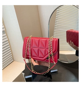 Detailed view of red quilted leather chain bag with geometric stitching and gold hardware