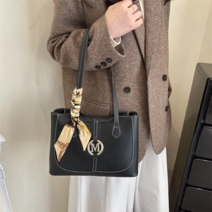 Black tote bag with white contrast stitching, golden M buckle and silk scarf detail
