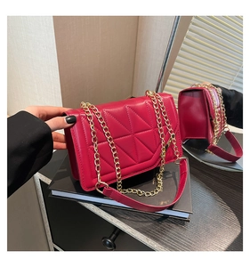 Macro detail of red quilted bag featuring geometric patterns and gold chain strap