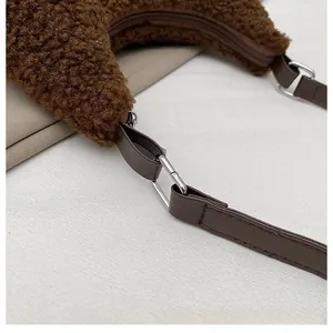 Detailansicht aus braunem Teddy-Fleece-Stoff mit Lederriemen und silberner Metallschnalle