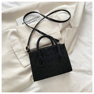 Détail d'un sac à main noir à motif léopard avec bandoulière et finitions dorées