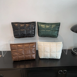 Sacs à main matelassés en quatre couleurs présentés sur un support en acrylique