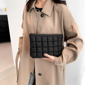 Chic black quilted puff clutch handbag for women styled with a beige trench coat