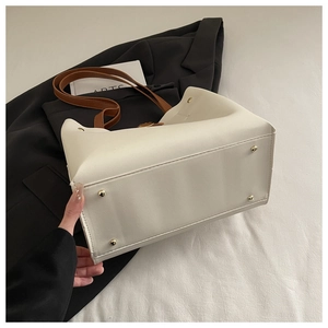 Détail du fond d'un sac cabas blanc avec rivets dorés et poignées en cuir marron