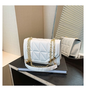 Detail of white quilted handbag with geometric pattern and gold chain strap
