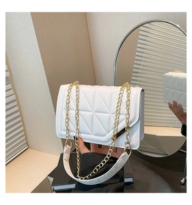Detailed close-up of white quilted leather bag texture with elegant gold chain strap
