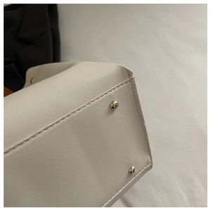 Détail du sac à main en cuir beige avec coutures de base et pieds dorés en métal