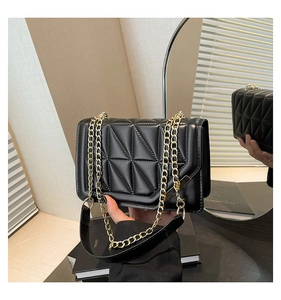Detailed view of the black quilted geometric bag with gold chain strap in a lifestyle setting