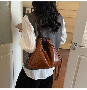 Vue latérale d'un sac cabas en cuir marron vintage porté par un mannequin en studio