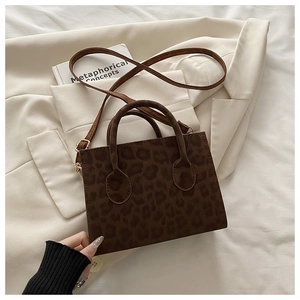Détail d'un sac à main léopard avec boucles dorées sur un tissu texturé blanc