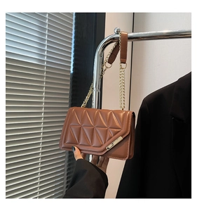 Detail of the brown geometric quilted handbag with gold chain strap and square metal buckle