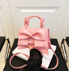 Roze handtas met grote strik en gedraaid touwhandvat detail op witte boeken