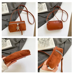 Détails d'un sac bandoulière en daim marron avec pendentif robot argenté et sangle réglable