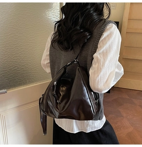 Détail d'un sac hobo en cuir marron foncé avec texture brillante et logo