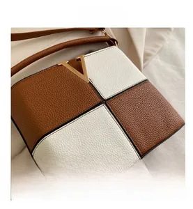 Close-up of contrast stitching on brown and white leather bucket bag with V-shaped buckle