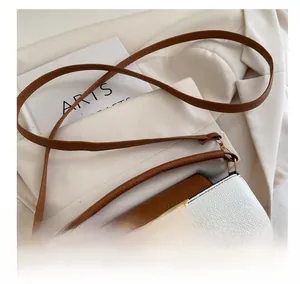 Macro shot of gold V logo on brown and white pebbled leather bucket bag flap