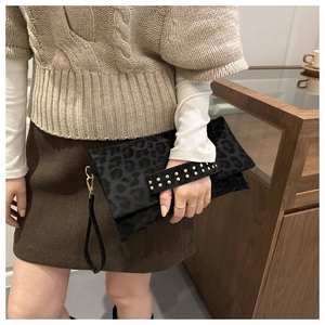 Dettaglio della pochette leopardata nera con borchie dorate e cinturino rimovibile