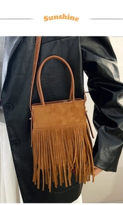 Close-up of brown suede bucket bag with long fringe tassels and metallic hardware detail