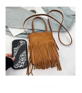 Detailed view of a brown tassel bucket bag next to a phone for size comparison