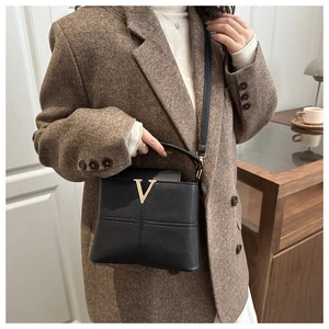 Detail of black pebbled leather handbag with gold V metal logo for office styling