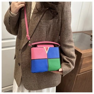 Detail of color-block leather bucket bag with gold hardware and pink shoulder strap