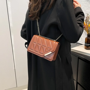 Brown quilted crossbody bag with gold chain strap shown in a modern lifestyle setting