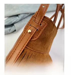 Close-up of brown fringe handbag featuring premium gold metal hardware and smooth leather