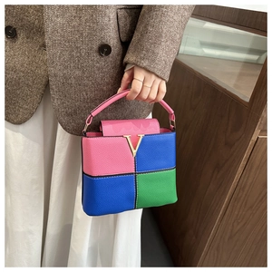 Close-up of tricolor leather bucket bag featuring pink blue green panels and V-logo