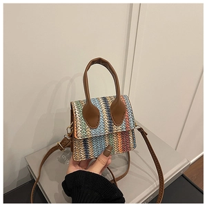 Detail of colorful woven straw bag with premium brown leather strap and hand-woven texture