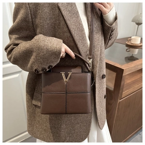 Detail of brown litchi grain leather bag with a vintage gold V-buckle and cross stitching