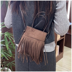 Detail of vintage bohemian dark brown suede bag with long fringe tassels shown on a model