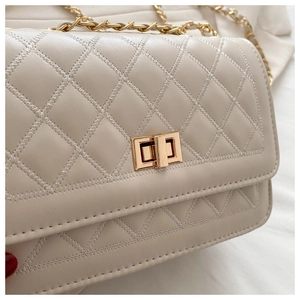 Detailed macro of beige quilted pattern leather and gold-tone twist lock buckle