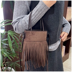 Close-up of brown suede tassel handbag with bohemian fringe detailing and long handles
