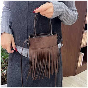 Detail of dark brown suede bucket bag featuring long fringe tassels and vintage design
