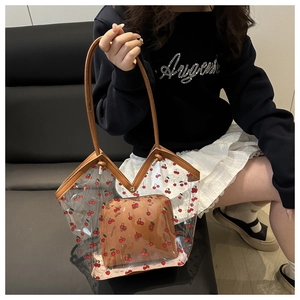 Detail of transparent PVC cherry tote bag with brown leather handles and inner pouch
