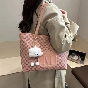 Detail view of pink PU tote bag with M-pattern print and a white plush cloud charm