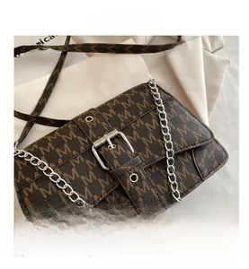 Vue détaillée du sac bandoulière vintage marron avec motif M et boucles argentées