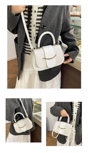 Close-up of white woven leather handbag with elegant crescent gold metal clasp detail