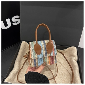 Macro shot of mini rainbow woven bag with brown leather handles and golden metal hardware