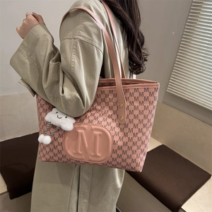 Close-up of pink PU leather tote bag with M-pattern and white cloud plush charm