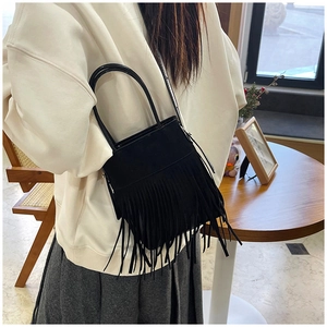 Detail of a black bohemian bucket bag featuring long fringe tassels in a lifestyle setting